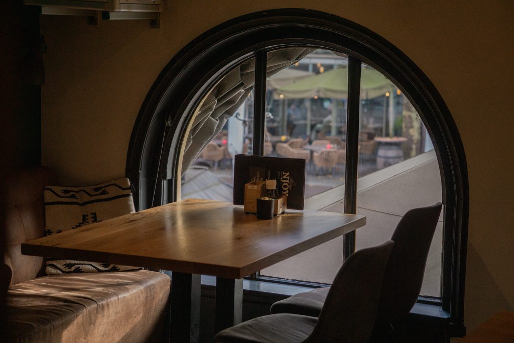 Sfeervol zithoekje bij NJOY Tapasrestaurant Kampen met menukaart op tafel en uitzicht op het Plantageplein.