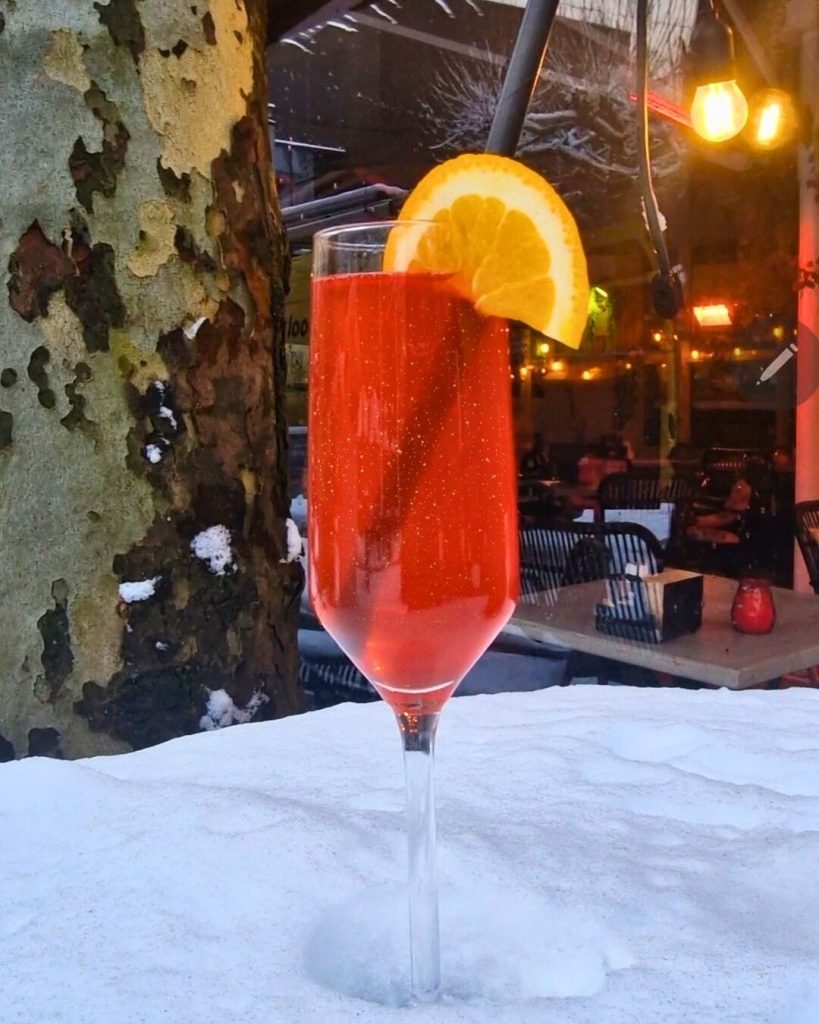 Happy New Year cocktail met Licor 43 en prosecco bij NJOY Kampen, geserveerd met glitters en sinaasappel in winterse setting