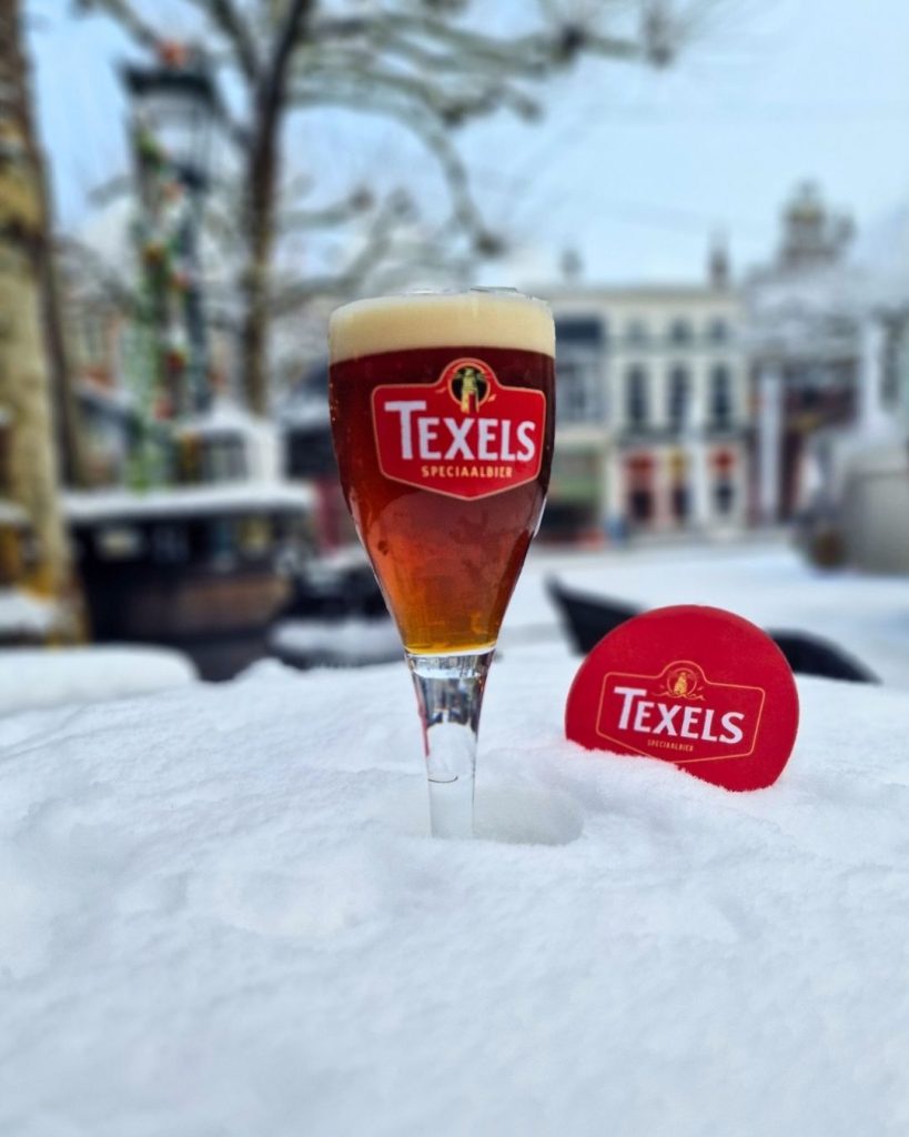 Texels Noorderwiend winterbier uit de tap bij NJOY Kampen, geserveerd in glas op hoge poot in winterse setting
